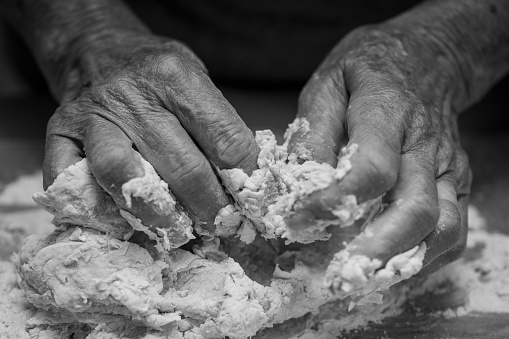 Grandmother's hands on bread dough - home baking