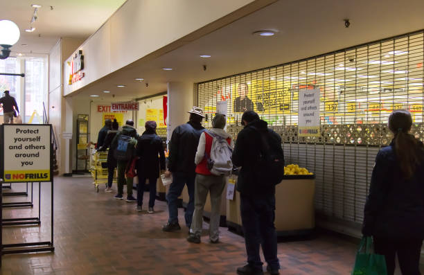 la gente está haciendo cola para entrar en no frills store practicando distancias sociales entre sí debido a covid-19. - west end fotografías e imágenes de stock