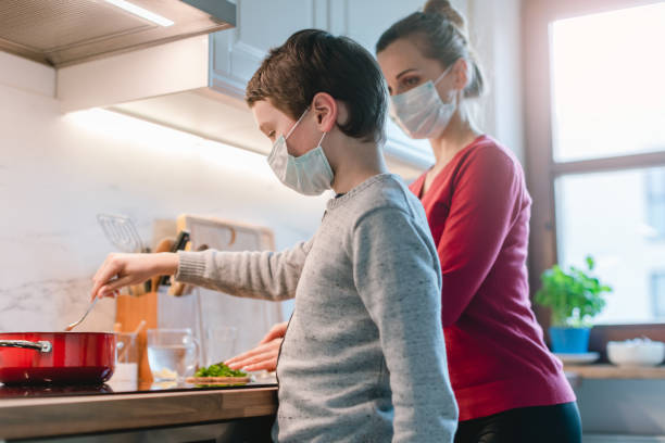 Mother and son cooking at home during the crisis time Mother and son cooking at home during the crisis time wearing masks curfew stock pictures, royalty-free photos & images