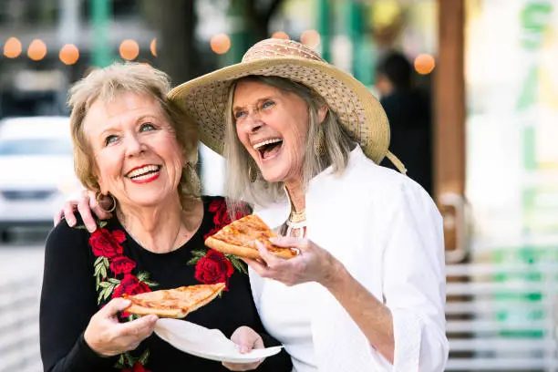 Photo of Senior Women Eating Street Food and Laughing