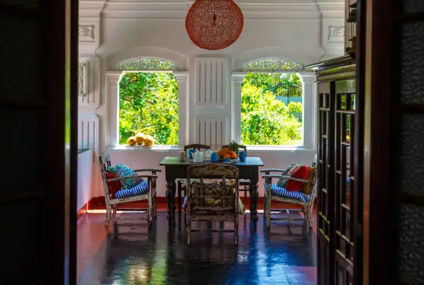 Photo of Verandah of an old Dutch-style Villa, with an old table and authentic frescoes, in the Windows of tropical garden, Sri Lanka