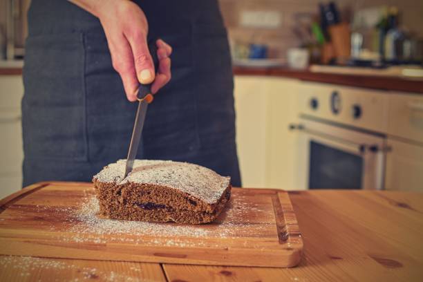 Man cutting classic gingerbread in traditional kitchen. A classic gingerbread recipe. Family home bakery, cooking traditional festive sweets. Man cooking food. Close-up.