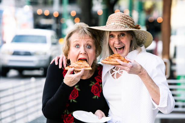 istock Senior Women Taking Big Bites of Pizza 1213779682