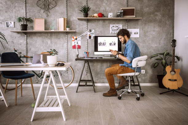 Quick Break To Text Some Messages Young Man Working In Comfort of His Home, Sitting On Desk Taking Shorter Break To Text Some Messages home office chair stock pictures, royalty-free photos & images