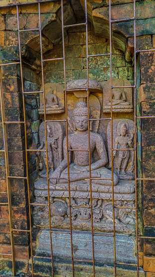 A Buddha statue in wall with 4 small statue near .This statue on a steel jell . Ratnagiri, jajpur, odisha, Ancient sculpture of lord Buddha at Ratnagiri,orissa(Odisha).A heritage tourist spot of India, Bhubaneswar temple city, odisha monuments