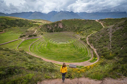 Female tourist exploring the circular Inca terraces of Moray, an archaeological site in the Sacred Valley of the Incas, Cusco Region, Peru, South America.