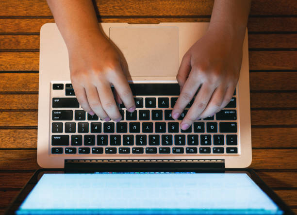 istock woman's hands working on the computer at home, wooden desk background 1213785506