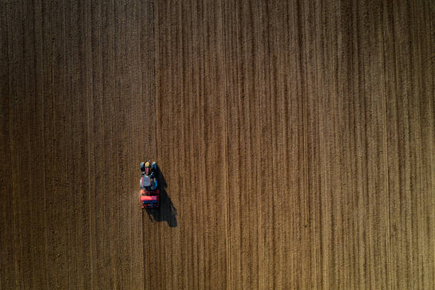 istock Farm tractor and seed drill sowing field, aerial view 1213786355
