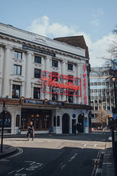 kobieta przechodząca obok neonu pułapka na myszy na fasadzie st martins theatre, londyn, wielka brytania. - agatha christie zdjęcia i obrazy z banku zdjęć