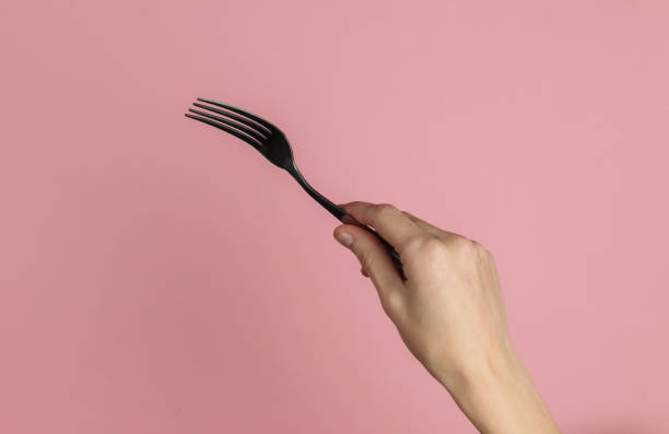 istock Female hand holds a fork on pink pastel background. Top view. Studio shot 1213800523