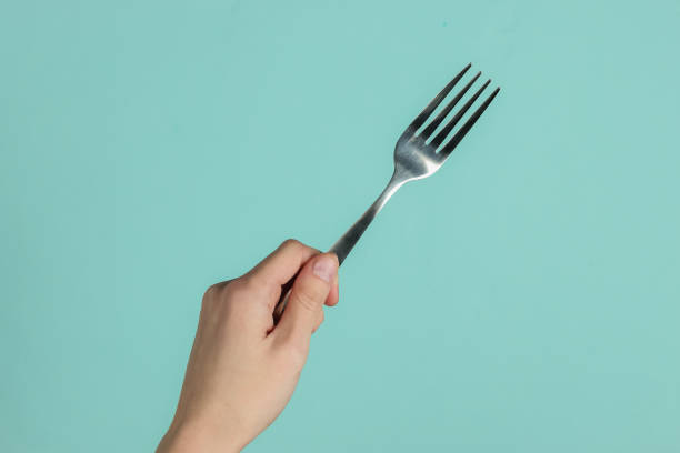 istock Female hand holds a fork on blue pastel background. Top view. Studio shot 1213800558