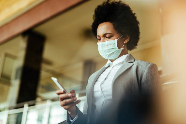 istock African American businesswoman text messaging on cell phone while wearing protective mask at the airport. 1213802534