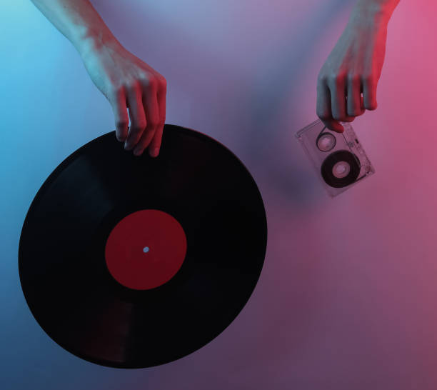 istock Retro wave 80s. Hands holding vinyl record and audio cassette. Creative pop art pink blue neon color. Trendy gradient illumination. Night light 1213805422