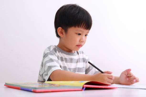 istock Little boy at his desk doing homework against white background. 1213805843