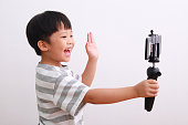 istock Cheerful little boy using smartphone and mini tripod filming video, vlogging 1213805868