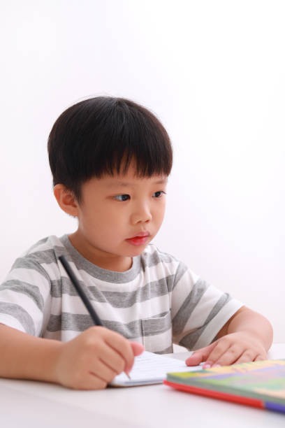 istock Little boy at his desk doing homework against white background. 1213805869