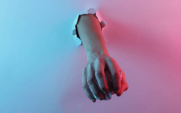 istock Hand holding crumpled paper ball through torn hole. Creative pop art pink blue neon color. Trendy gradient illumination. Night light 1213806528