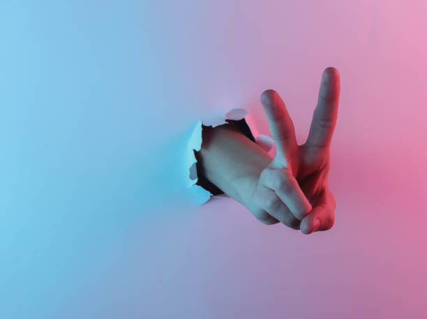 istock Mystical halloween concept. Hand shows V gesture through a torn hole.