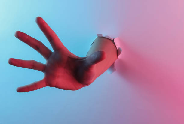 istock Mystical halloween concept. Hand through a torn hole. Creative pop art pink blue neon color. Trendy gradient illumination. Night light 1213806562