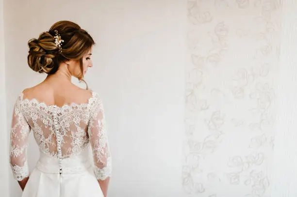 Photo of Portrait of a beautiful stylish bride with an elegant hairstyle view from the back. Wedding, people, fashion and beauty concept - bride in wedding dress. Back view.