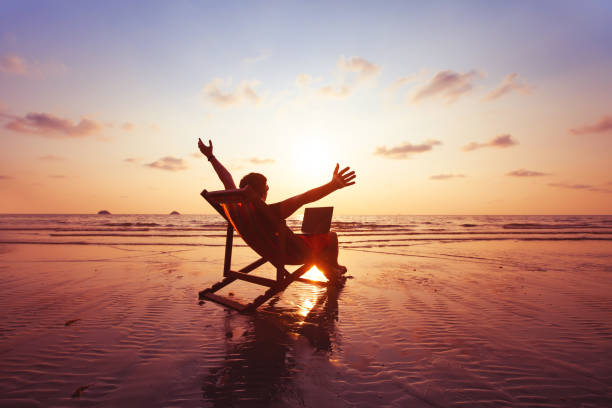 freelancer z laptopem pracującym na plaży, praca na zewnątrz - summer idyllic carefree expressing positivity zdjęcia i obrazy z banku zdjęć