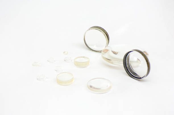 Optical lenses as spare parts for lenses, microscopes and other optical devices. Replacing lenses with new ones. Glass lenses isolated on a white background close-up.