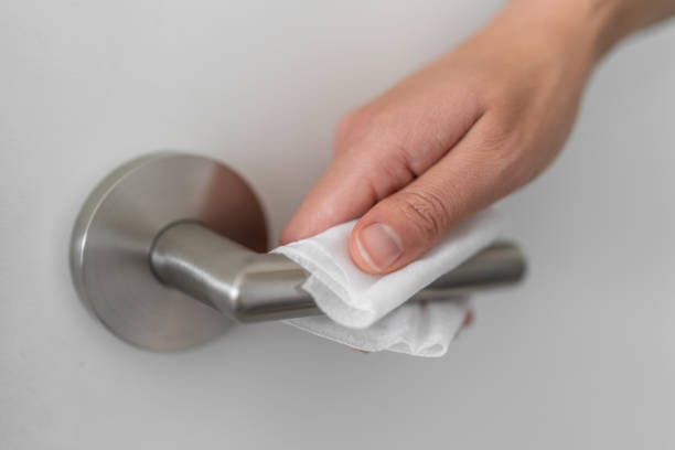 Coronavirus COVID-19 Prevention cleaning woman wiping doorknob with antibacterial disinfecting wipe for killing corona virus on surfaces or touching public bathroom handle with tissue Coronavirus COVID-19 Prevention cleaning woman wiping doorknob with antibacterial disinfecting wipe for killing corona virus on surfaces or touching public bathroom handle with tissue. doorknob stock pictures, royalty-free photos & images