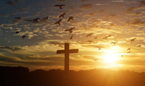 Silhouette of catholic cross at sunset background.