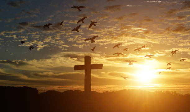 Silhouette of catholic cross at sunset background. stock photo