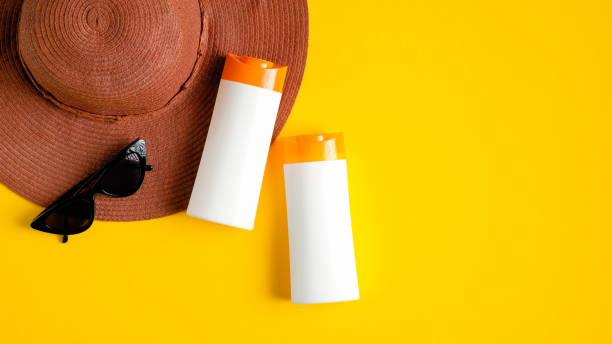 istock Sunscreen cream in two white plastic bottles, sunglasses, beach hat on yellow background. Sun protection, sunblock cosmetic product, summer skin care concept. Flat lay, top view 1213817968
