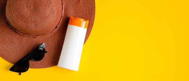 istock Sunscreen cream in white plastic bottle, sunglasses, beach hat on yellow background. Sun protection, sunblock cosmetic product, summer skin care concept. Flat lay, top view 1213817973