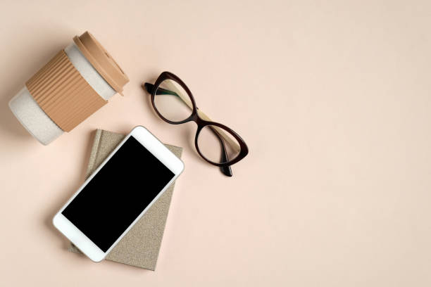 istock Flat lay feminine home office workspace with paper notepad, glasses, reusable bamboo coffee cup, phone with blank screen mockup. Cozy female office desk concept. 1213818914