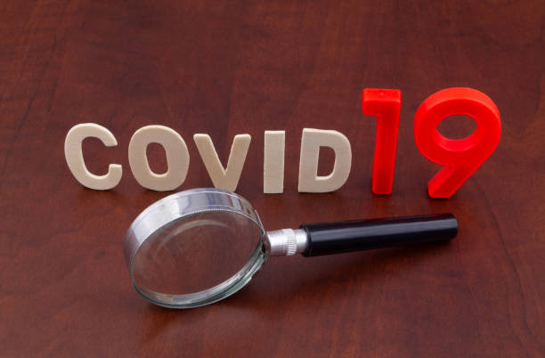 istock Magnifying glass and word covid19 on table. 1213819044