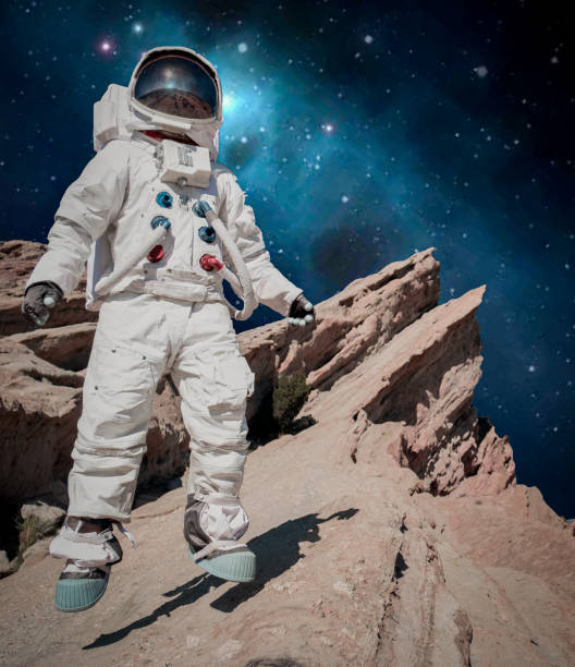 Spaceman Floats of a Blue Planet I single astronaut figure floats above the surface of a rocky planet. The camera is low making the astronaut look epic and heroic. The sky behind him is a richly saturated blue galaxy. It's weird, unique, doesn't make any sense... and yet for some reason, it's really cool. cosplay photos stock pictures, royalty-free photos & images