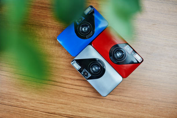 caméras de film analogiques colorées de 35mm se trouvant dans l’arrangement près de l’autre sur une table en bois - version 3 flash photos et images de collection