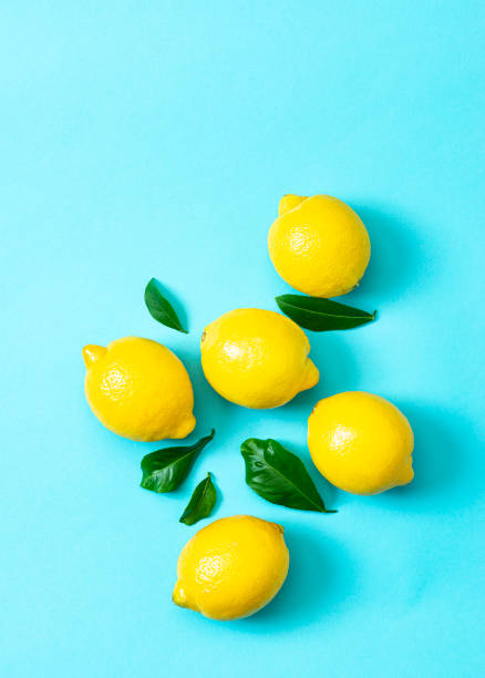 istock Ripe lemons flat lay with leaves on blue background 1213825794