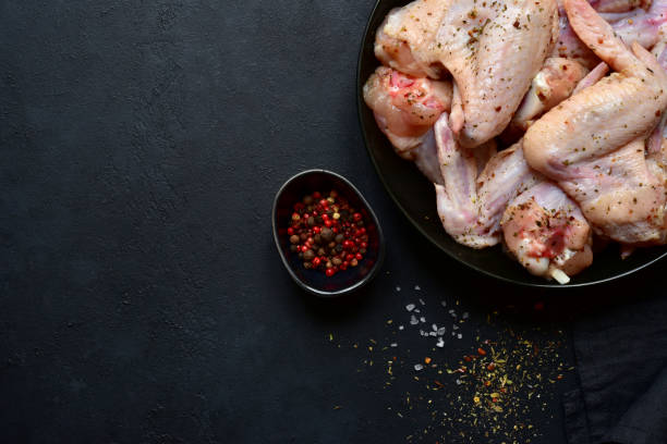 istock Raw marinated chicken wings on a black plate 1213826371