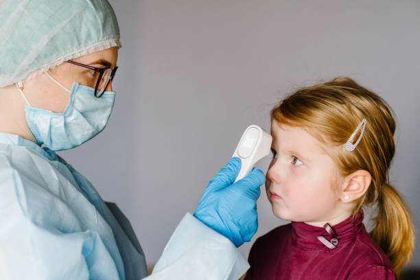 coronavirus. sjuksköterska eller läkare kontrollerar flickans kroppstemperatur med infraröd panna termometer (pistol) för virussymtom - epidemiska utbrott koncept. hög temperatur. - iranian girl bildbanksfoton och bilder