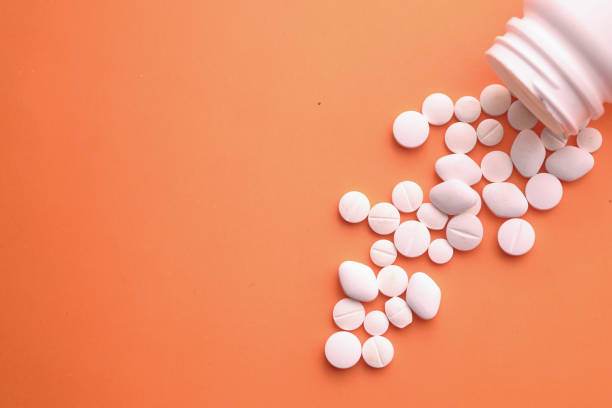 istock close up of white pills spilling on a white background 1213827824