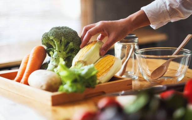 istock A woman chef holding and picking a fresh corn from a vegetables tray 1213831506