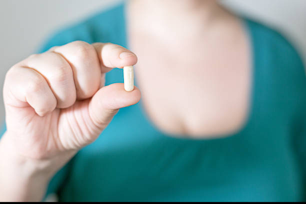 istock Woman dressed in green with pill in the foreground 1213836563