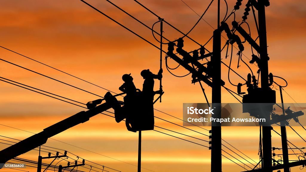Silhouette two electricians with disconnect stick tool on crane truck are working to install electrical transmission on power pole Silhouette two electricians with disconnect stick tool on crane truck are working to install electrical transmission on power pole with blurred sunrise sky background in technology concept Power Line Stock Photo