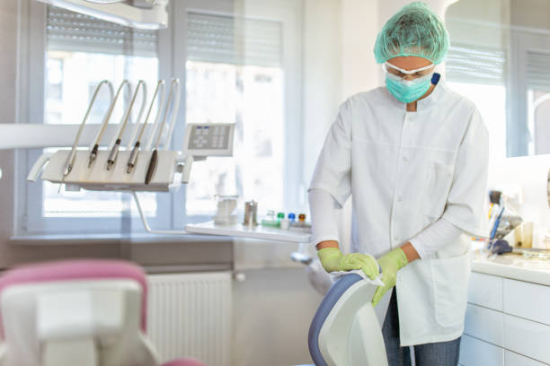 врач-женщина чистит стоматологический кабинет - dentists chair people care medical equipment стоковые фото и изображения