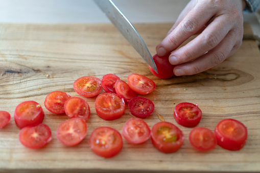 cutting cherry tomatoes on cutting board