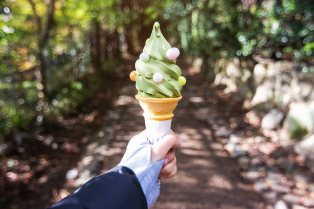 mão de mulher segurando chá verde sabor doce servir cone com pouco doce de bola na árvore da natureza bokeh em um parque. - soft serve ice cream - fotografias e filmes do acervo