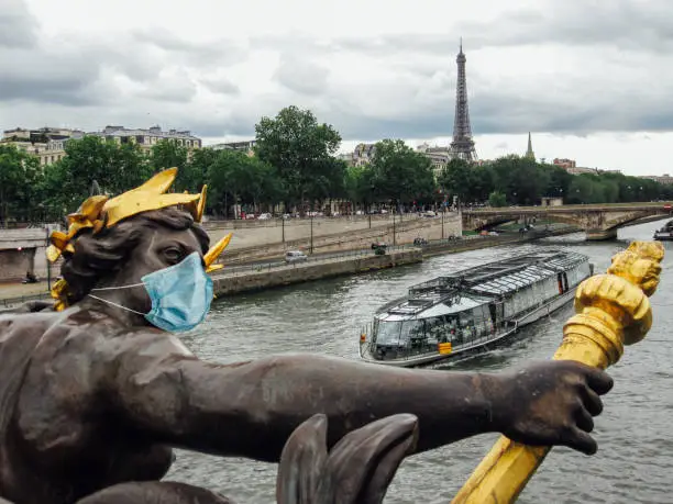 Statue at Alexander III bridge wearing a surgical face mask as a symbol of the Paris lockdown caused by coronavirus outbreak