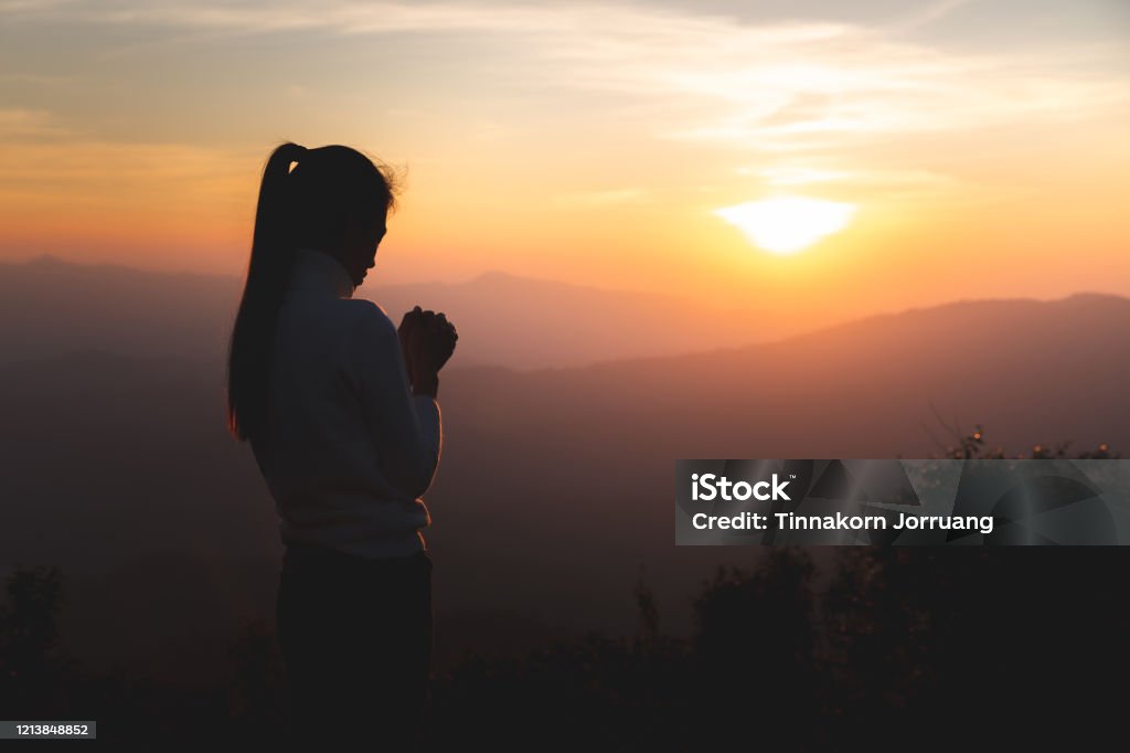 Silhouette of young  human hands  praying to god  at sunrise, Christian Religion concept background. Praying Stock Photo