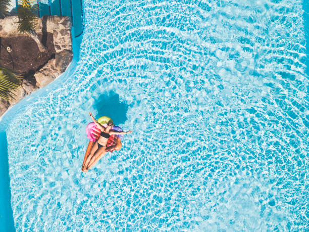 美しい若い女性は、青いクリアスイミングプールでインフレータブルアイスクリームリロでリラックスして横たわって - 楽しんでいる人々のためのホテルリゾートのコンセプトで休日の夏休� - floating on water women swimming pool water ストックフォトと画像