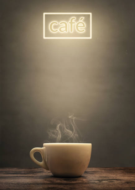 Steaming cup with illuminated café sign A white coffee cup on a rustic wooden surface. The cup gets illuminated from above by a "café" sign. Copy space in the middle of the poster. tasse café stock pictures, royalty-free photos & images