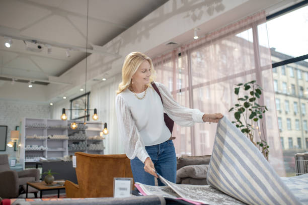 istock Woman in a blouse and jeans looking at carpet samples. 1213853842